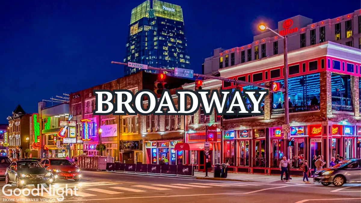 A vibrant street scene with neon signs, busy sidewalks, people walking, and tall buildings, evoking the energy and nightlife of Nashville's downtown entertainment district.