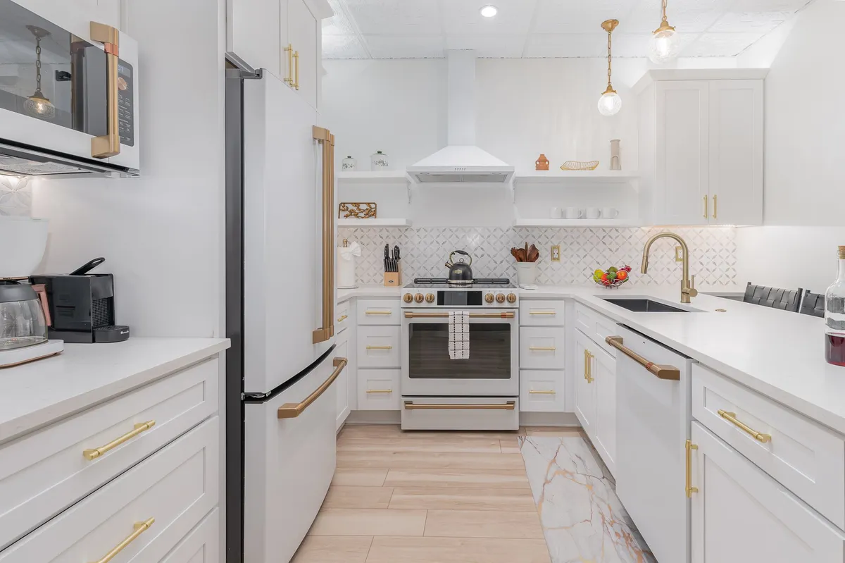 A bright, stylish kitchen with a stainless steel oven, gold-accented fixtures, white cabinetry, and a geometric tile backsplash. The setup suggests a space ready for both cooking and entertaining, with the coffee maker visible on the counter reinforcing the energizing morning routine referenced in the section.